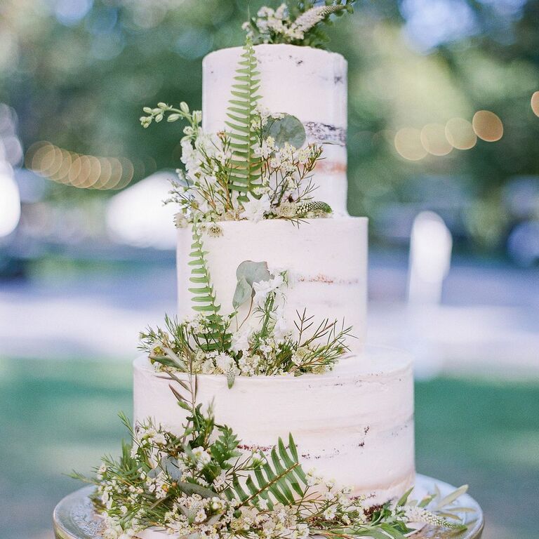 Elegant multi-tier wedding cake with floral accents in a ballroom setting