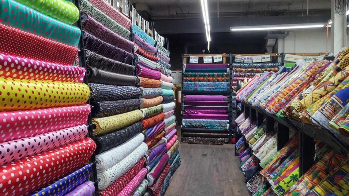 A large fabric warehouse showing rows of colorful textile rolls on industrial shelving